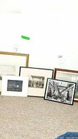 Group shot of four framed black-and-white works and one matted Zalon print on floor