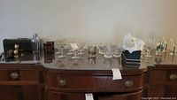 Wide shot of the entire collection on a wooden table including stemmed glasses, cocktail shaker, souvenir glass, and bar tools