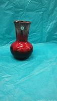 Front and side view of the ceramic vase showing the red and black glaze with glossy finish.