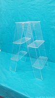 Angled view of the clear acrylic display shelf showing the five angled tiers and ladder-like structure