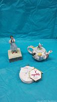 Full view of the three items: Dorothy music box, Alice in Wonderland teapot, and unicorn coasters