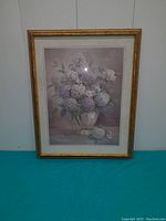Full view of the framed large picture featuring a floral bouquet in a vase with a gold frame and glass cover.