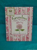 Front cover of the memory book titled 'Grandma Tell Me Your Story' by Susan Branch with floral and striped pink design.