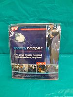 Front view of the Snazzy Napper travel set packaging showing the blanket and eye mask with usage illustrations.