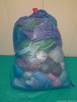 Blue mesh bag filled with various yarn skeins of different colors and sizes, some partially used.