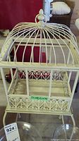 Full view of metal bird cage showing dome-shaped top and scrollwork detailing on base.
