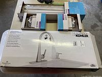 Overview of Kohler faucet box alongside Moen Boardwalk towel rings and towel bar in original boxes