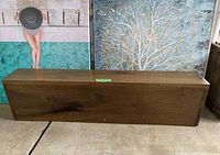 Front view of the wooden fireplace mantel showing smooth surface, wood grain pattern, and overall rectangular shape.