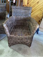Front view of brown wicker armchair without cushion, showing the woven pattern and armrests.