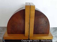 Front and side view of the two wooden bookends showing the curved dark wood face with light wood base and spine, arranged vertically and touching.