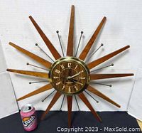 Front view of clock with wooden rays and metal rods, soda can for scale