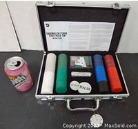 Poker set inside an open metal carrying case showing poker chips, playing cards, dice, dealer buttons, and a pop can for size comparison.