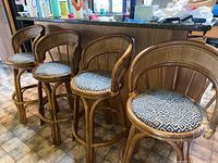 Front view of the four bamboo bar stools with black and white geometric fabric seats lined up together.