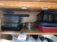Shelf with various glass brownie and casserole dishes mostly clear glass and one ceramic red dish.