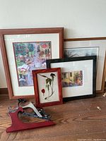 Four colorful framed prints and four hinged stands arranged on a wooden surface