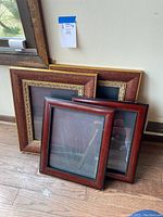 Two pairs of picture frames stacked against a wall, showing varying sizes and finishes