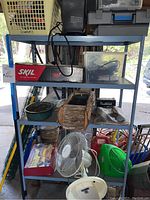 Wide view of metal shelving unit holding assorted household items such as tool boxes, bags, fans, and storage baskets.