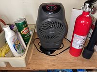 Sunbeam space heater, fire extinguisher, cleaning supplies on wood surface