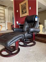Recliner and ottoman, side view showing leather upholstery and cherry wood base