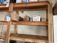 Wooden shelves with various boxes including the ISHI tile cutter box, and smaller boxes with nails and knobs visible