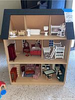 Front view of Melissa & Doug wooden dollhouse with three levels fully furnished with dollhouse furniture including beds, crib, bathroom suite, vanity, chairs, and tables.