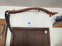 Two wooden scythes with curved shafts and dark metal blades hanging above a door.