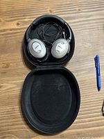 Bose QuietComfort headphones folded inside black zippered protective carrying case with audio cable coiled inside.