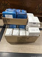 Overview of lot showing several nLight blue boxes and white module boxes stacked in a cardboard container