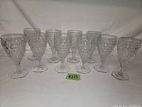 Set of 10 vintage clear glass Fostoria American goblets with hexagonal bases and textured geometric pressed pattern.