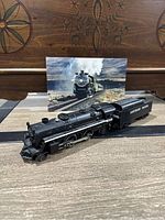 Black Lionel Southern Pacific steam model train engine and tender on display with photo backdrop.