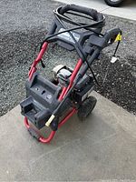 Front angled view of the red and black pressure washer showing engine and frame condition.