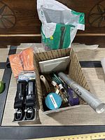 Overview of various items outside and inside cardboard box including straps, orange towels, and bag of absorbent material
