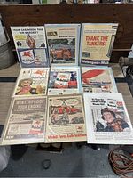 Wide view of all 9 vintage Mobil Oil advertisements arranged on a wooden surface.