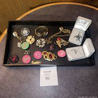 Top view of assortment of costume jewelry including pins, buttons, bracelets, and necklaces