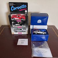Photo showing three die cast Corvette model cars sealed on Corvette Collection card and the boxed 1963 Corvette Sting Ray Christmas ornament by Franklin Mint with certificate and plastic cover on table.
