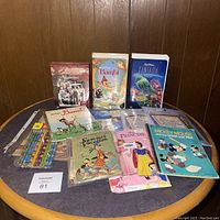 Photo of lot on round table, showing Disney VHS tapes and children's books