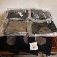 Eight copper-infused knee support sleeves in plastic packaging and unpackaged on surface, black and beige colors visible.