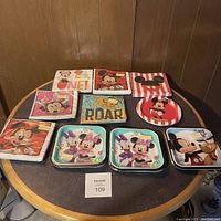 Top-down view of all plastic plates and napkins arranged on the table showing different Disney character designs and color schemes.