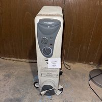 Front view of Pelonis heater showing control panel with two knobs and indicator lights, unit standing upright on caster wheels.