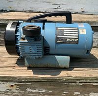 Side view of blue PneuMotive air compressor with black handle, showing compressor unit and motor.