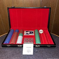 Poker chip set displayed open with chips, cards, dice, and dealer button visible in the black case with red interior.