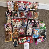 Full view of 22 Ty Beanie Babies and related collectibles, some in original plastic packaging, on carpeted floor.