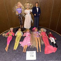 Photo showing all nine dolls, multiple Barbies and one Ken figure with varied outfits.