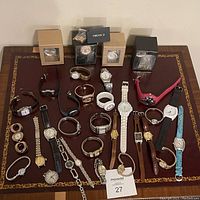 Overview of assorted women's wristwatches displayed on a table, showing variety in styles, colors, and bands, some boxed.