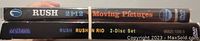 Photo showing the spines of two Rush DVDs: 'Moving Pictures' and 'Rush in Rio' 2-disc set.