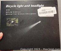 Photo of black box packaging displaying product name, LED life and discharge time, and small images illustrating the headlight beam and cyclist use.