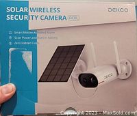 Photo of the Dekco Solar Wireless Security Camera DC8L box showing product image and key features such as solar power, wireless setup, and motion-activated alarm.