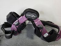Front angled view of purple Donjoy knee brace with black straps and hinges