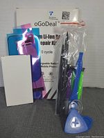 Photo showing the oGoDeal iPhone 8 battery replacement kit with battery, repair tools, adhesive strips, and instruction manual in clear packaging.