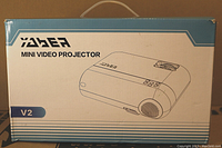 Box front showing YABER Mini Video Projector V2 branding and illustration of projector.